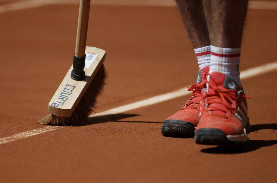 Con lo spazzolone, persino numerato - nella foto quello targato Court 2 , si puliscono le righe dalla sabbia rossa tra un game e l&#39;altro (Action Images)